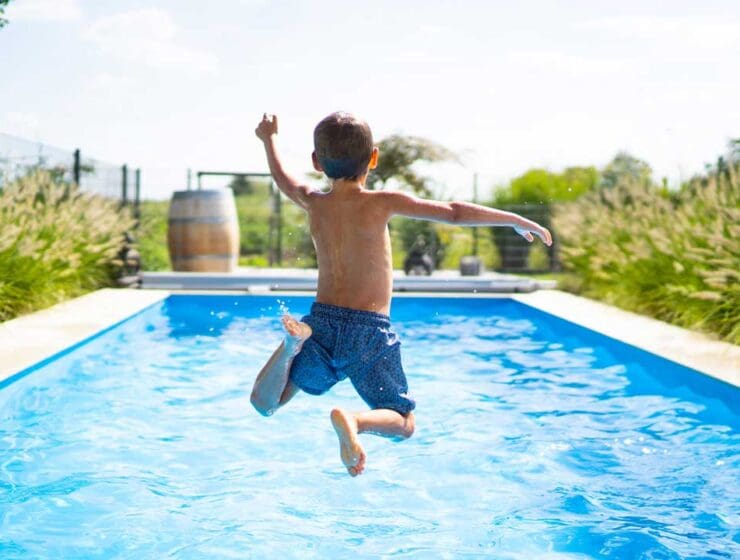 kid jumping into a blue pool