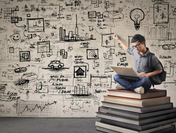 man sitting on stack of books with wall full of equations