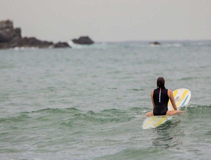 A photograph of a woman heading out to surf
