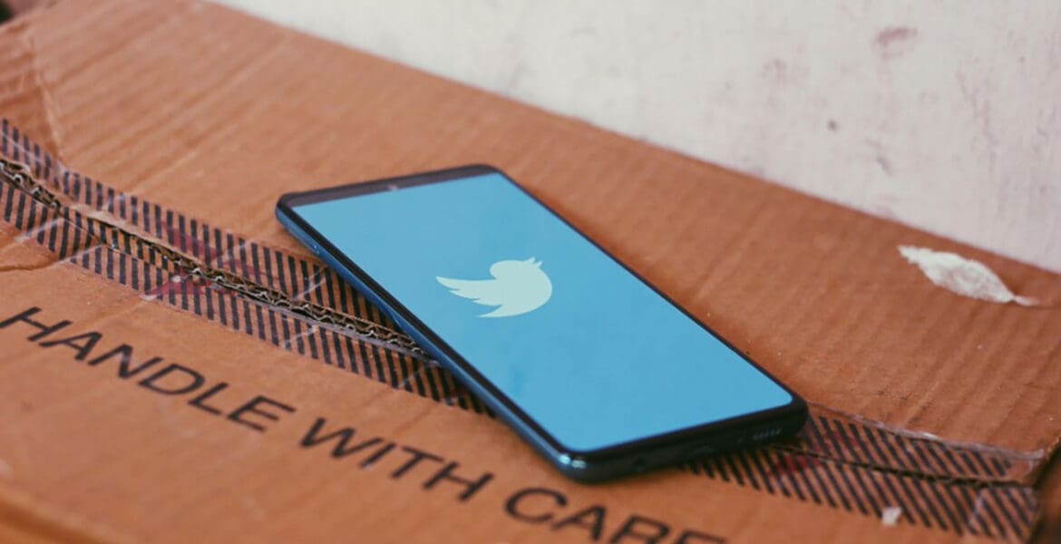 Phone displaying Twitter atop of a box that reads Handle With Care