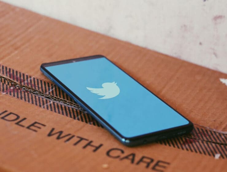 Phone displaying Twitter atop of a box that reads Handle With Care